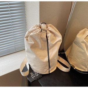 Close-up of beige drawstring bucket bag featuring lightweight textured nylon fabric