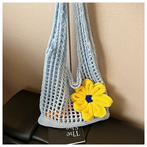 Detail of light blue knit mesh bag featuring a large yellow handmade crochet flower