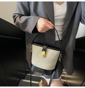 Modern canvas bucket bag with black leather trim and marble lock worn by a model