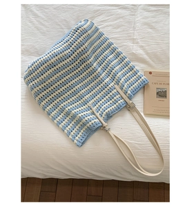 Detail of blue and white striped woven tote bag with leather straps and silver buckles