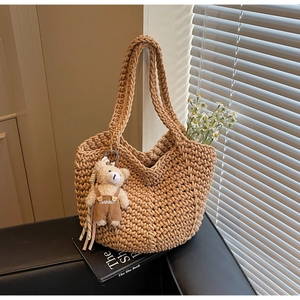 Detail of hand-woven crochet hobo bag with a cute bear charm and floral decorations