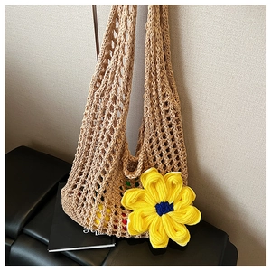 Detailed close-up of a handmade crochet bag with a vibrant yellow sunflower on a black bench
