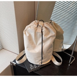 Detail of off-white nylon drawstring bucket bag with pleated texture and wide straps