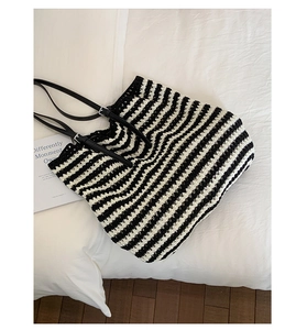 Detail of black and white striped crochet tote bag with elegant black leather handles