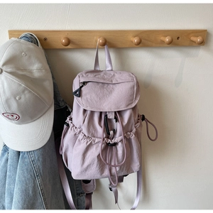 Zaino in nylon lavanda con tasche a coulisse e moschettone appeso a un gancio di legno
