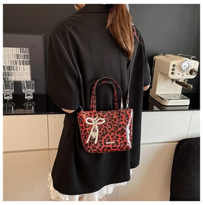 Detail of leopard print crossbody bag with pearl bow charm and adjustable shoulder strap