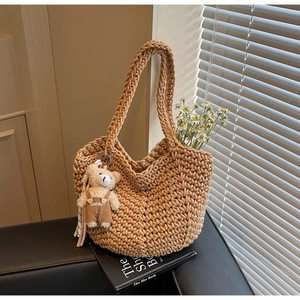 Detail of khaki hand-woven shoulder bag texture with cute teddy bear charm