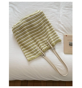 Detail of hand-crocheted straw tote bag with striped texture and leather straps