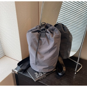 Detail view of dark grey drawstring bucket bag with durable nylon fabric and woven straps