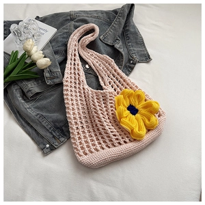 Close-up of pink crochet tote bag with a yellow knit sunflower detail for summer beach use