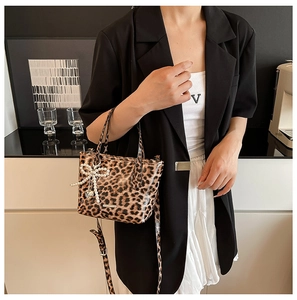 Detail of leopard print crossbody bag with pearl bow charm and heart metal pendant