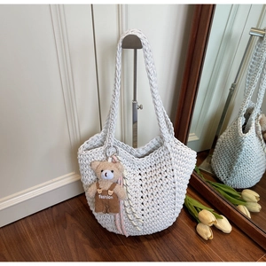Detail of white woven rope tote bag featuring a cute brown plush bear fashion charm