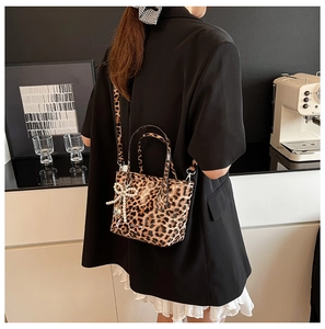 Leopard print crossbody bag with pearl bow pendant detail in a lifestyle setting