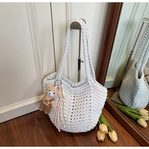 Detail of white hand-woven crochet shoulder bag with a cute teddy bear charm hanging