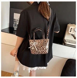 Detail view of crossbody leopard print bag with pearl bow charm and silver strap