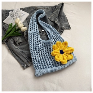 Close-up of sky blue crochet tote bag featuring a vibrant yellow knitted flower detail