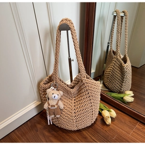 Detail of khaki hand-woven tote bag with honeycomb texture and cute bear charm