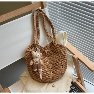 Detail of a brown woven tote bag with a cute bear charm on a stylish canvas chair