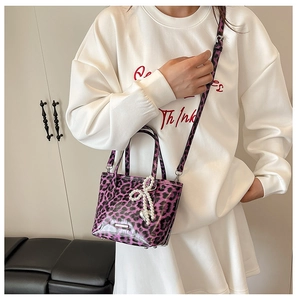 Detail of purple leopard print mini handbag with pearl bow charm and heart pendant