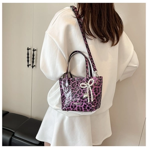 Detail of purple leopard print crossbody bag with pearl bow and silver heart pendant