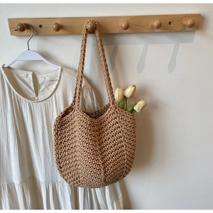 Detail view of khaki hand-woven crochet tote bag featuring white tulips in a home setting