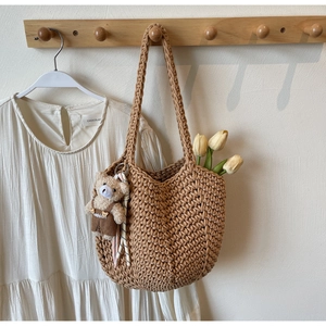 Detailed texture of brown hand-woven shoulder tote bag with a cute plush bear pendant
