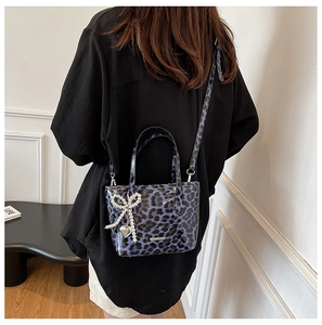 Purple leopard print crossbody bag with pearl heart charm on model in casual setting