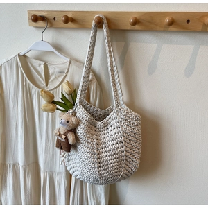 Detail of hand-woven cream crochet shoulder bag with teddy bear and tulip charm