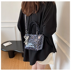 Detail of purple leopard print crossbody bag with pearl bow charm and glossy finish