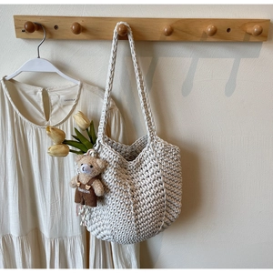 Detail of hand-woven cream white hobo bag with teddy bear charm and tulip decoration