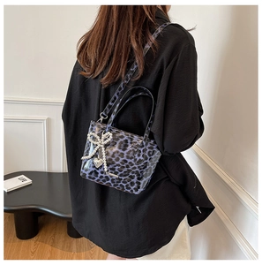 Detail of purple leopard print crossbody bag with pearl bow and silver heart pendant