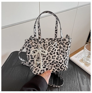 Detail of leopard print crossbody bag with pearl bow charm and silver heart pendant