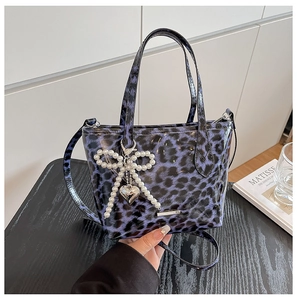 Detail of blue leopard print crossbody bag with pearl bow and silver heart charm
