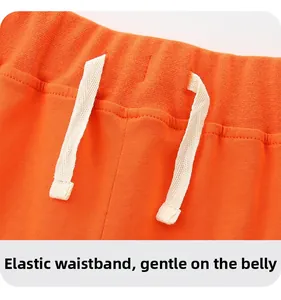 Detail of orange boys' knit pants featuring an elastic waistband and white drawstrings