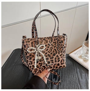 Close-up of leopard print crossbody bag with glossy finish and pearl bow charm