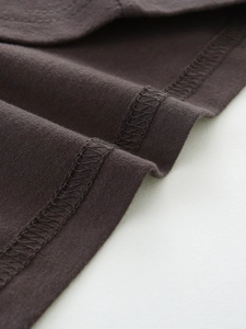 Détail de l'ourlet d'un t-shirt en coton marron foncé montrant la couture de haute qualité