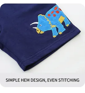 Détail de l'écusson dinosaure brodé et des coutures lisses sur le short bleu marine