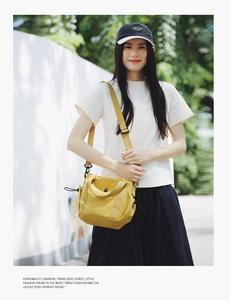Detailed view of bright yellow nylon crossbody bag featuring top handle and side drawstring