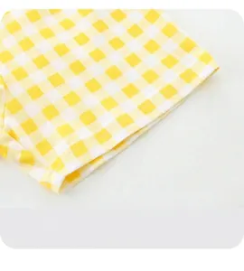 Detail of yellow gingham cotton shorts featuring wide-leg hem and fine stitching
