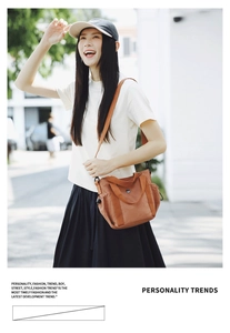 Detail of a brown canvas crossbody bag with drawstring side and wide shoulder strap