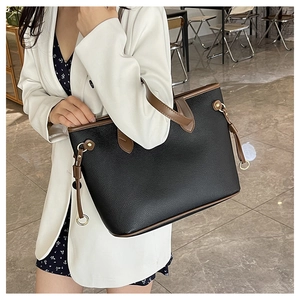 Detail of black lychee grain tote bag with brown contrast handles and gold hardware