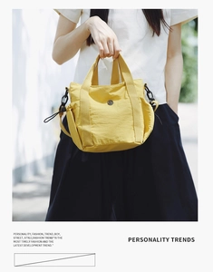 Detail of yellow nylon handbag with circular logo button and drawstring side pocket