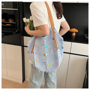 Detail of light blue knit tote bag with colorful sequins and brown leather straps