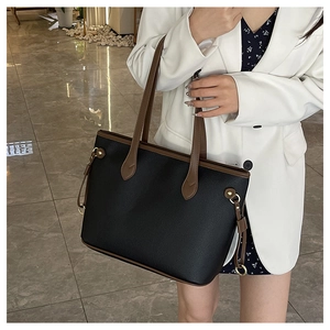 Detail view of large tote bag in black pebbled leather with contrasting brown straps