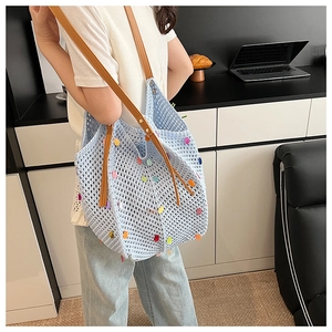 Detail of light blue crochet tote bag with colorful sequins and brown leather strap