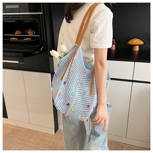 Detail of light blue knit tote bag with colorful 3D dots and brown leather tassel handles