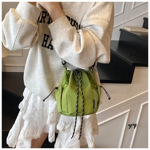 Detail view of grass green drawstring bucket bag with side mesh pockets and black strap hook