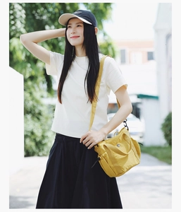 Close-up of bright yellow canvas crossbody bag with wide strap on a model outfit