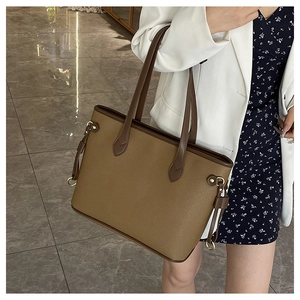 Detailed side view of brown textured leather tote bag with elegant golden metal ring accents
