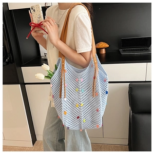 Detail of light blue crochet tote bag with colorful polka dots and brown leather straps